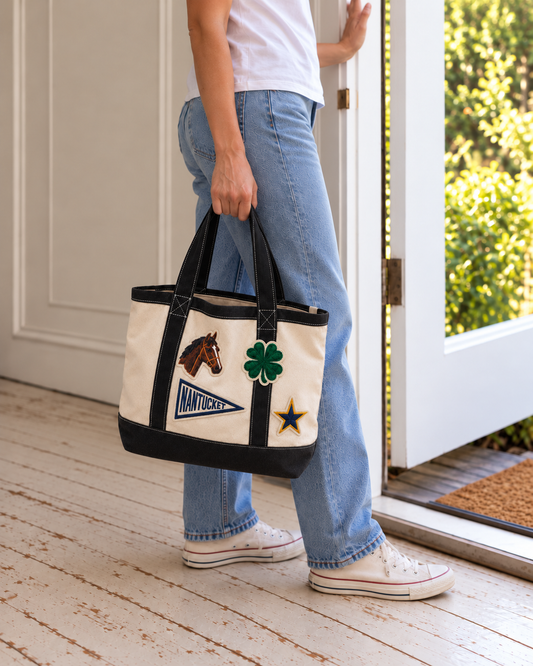 Woman carrying a natural and black patch tote in a doorway, shop small local gifts
