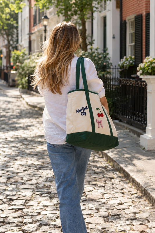 Woman walking a cobblestone street carrying a natural and green custom patch tote bag