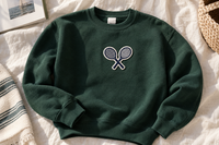 Forest green crewneck sweatshirt with a tennis rackets patch, laid flat